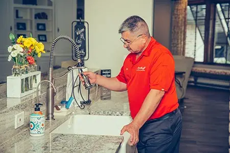 plumber performing Houston plumbing repairs in kitchen