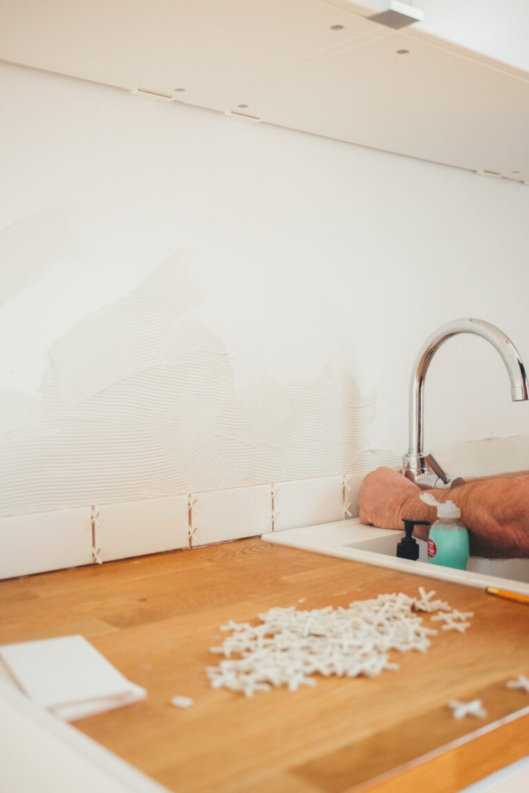 Person tiling kitchen sink backsplash during Houston kitchen remodeling