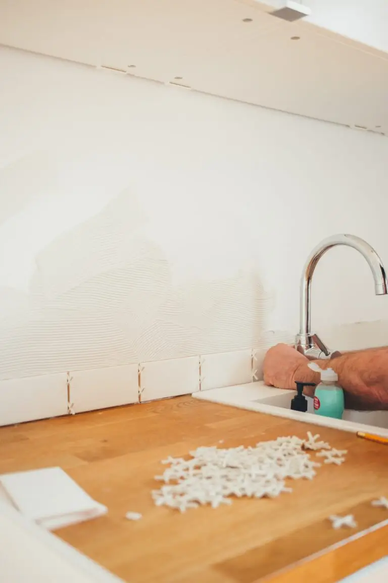 Person tiling kitchen sink backsplash during Houston kitchen remodeling