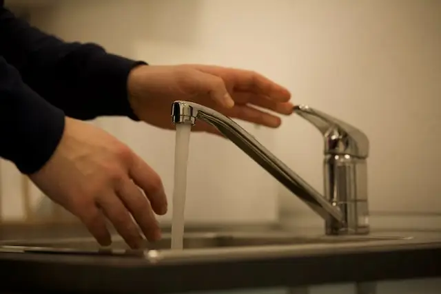 Houston residential plumber turning on faucet to test water pressure