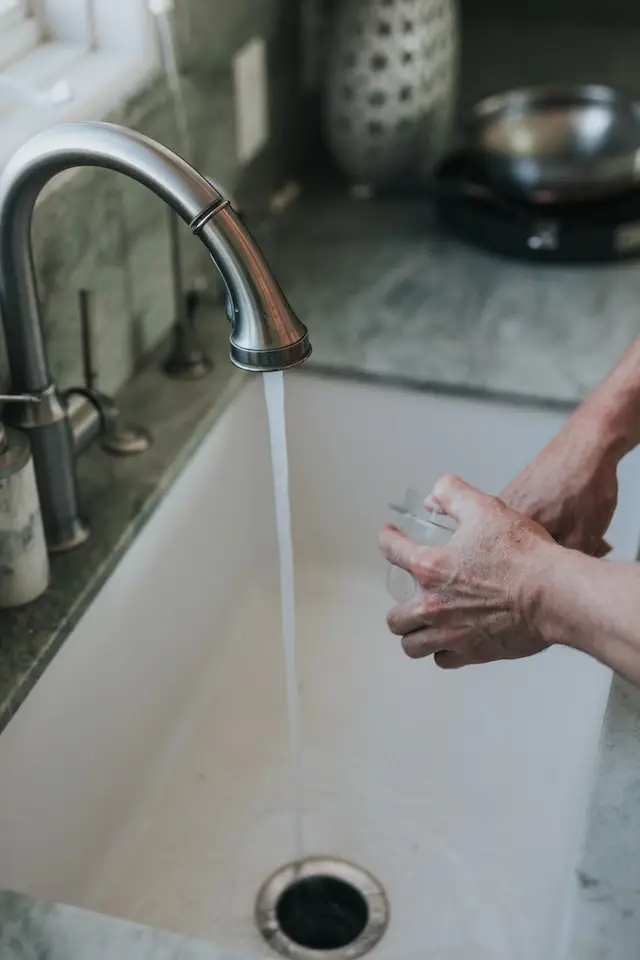 Person using kitchen sink that needs garbage disposal repairs