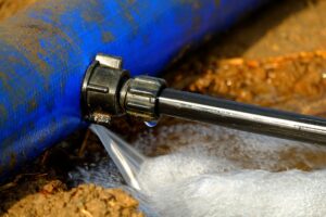 Blue pipe leaking water into ground at connection point that needs plumbing leak repairs.