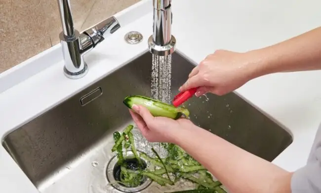 woman peeling vegetables in sink that had Houston garbage disposal repair