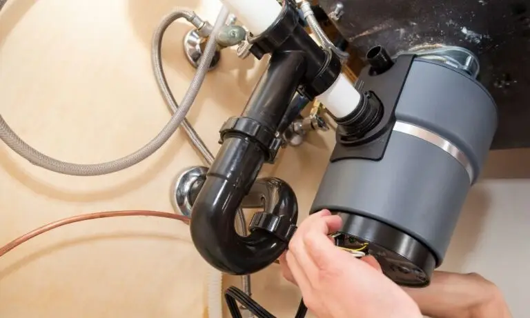 plumber completing Houston garbage disposal repair under sink